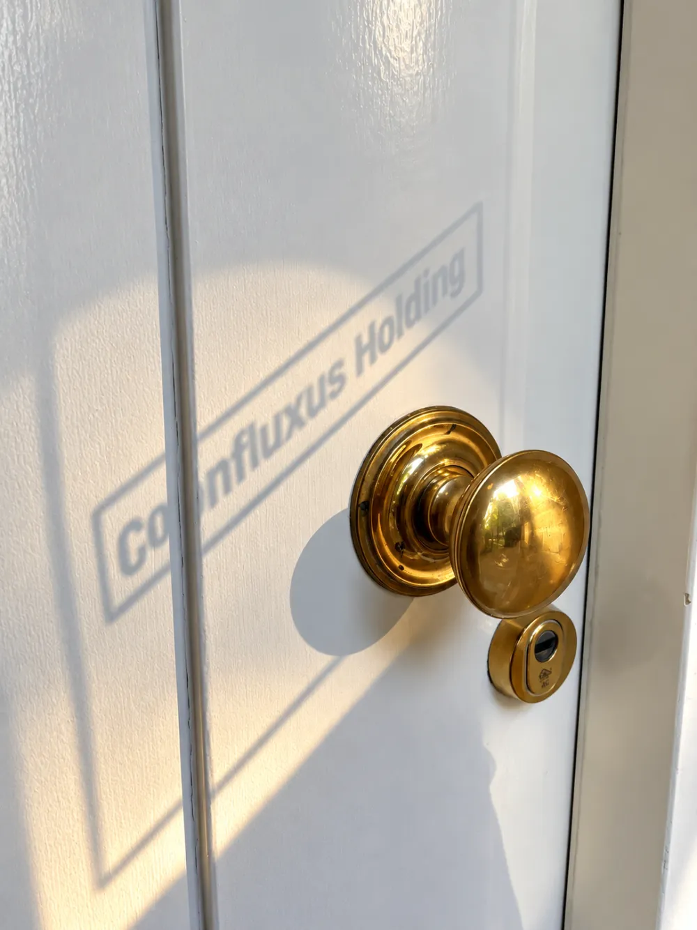 Voordeur met Confluxus Holding-logo in het zonlicht